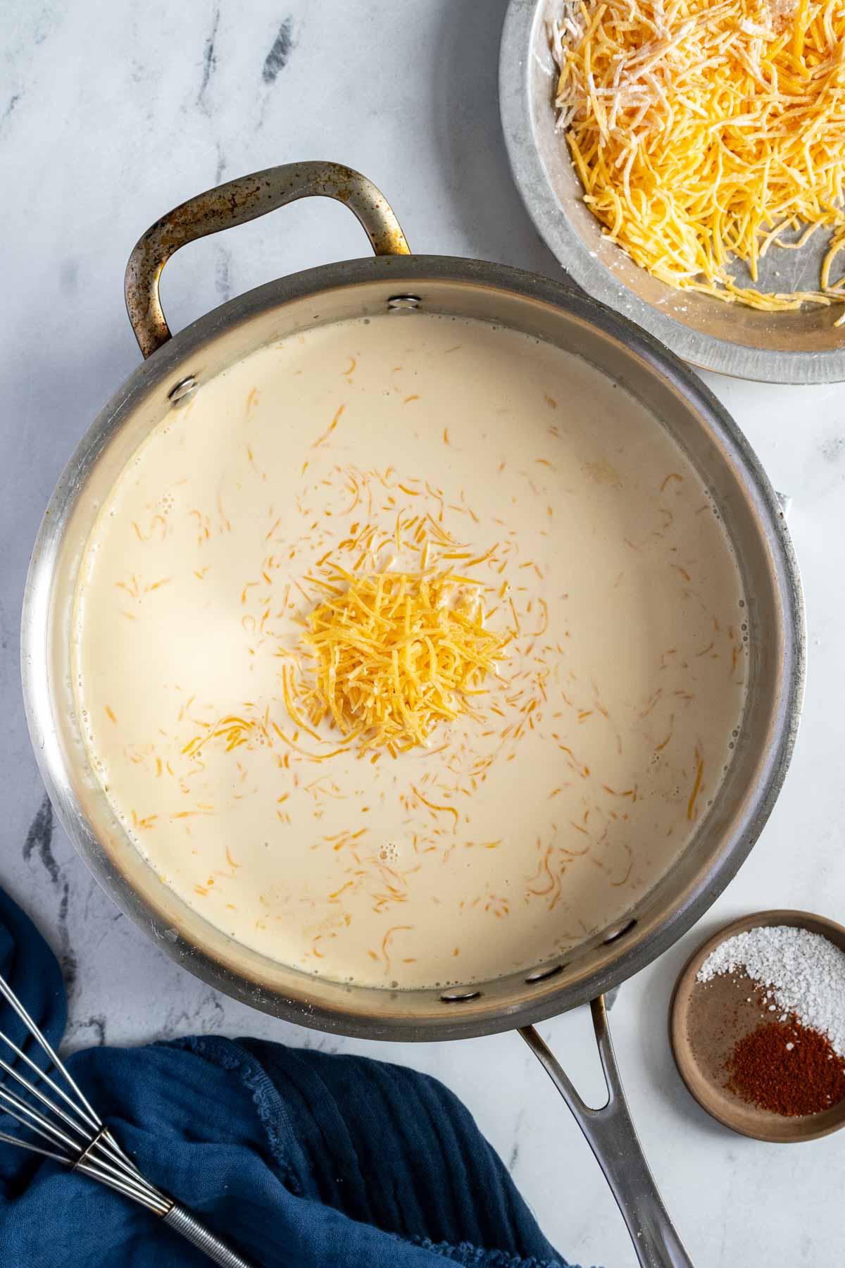 Making cheese sauce in a pan with cheddar cheese.
