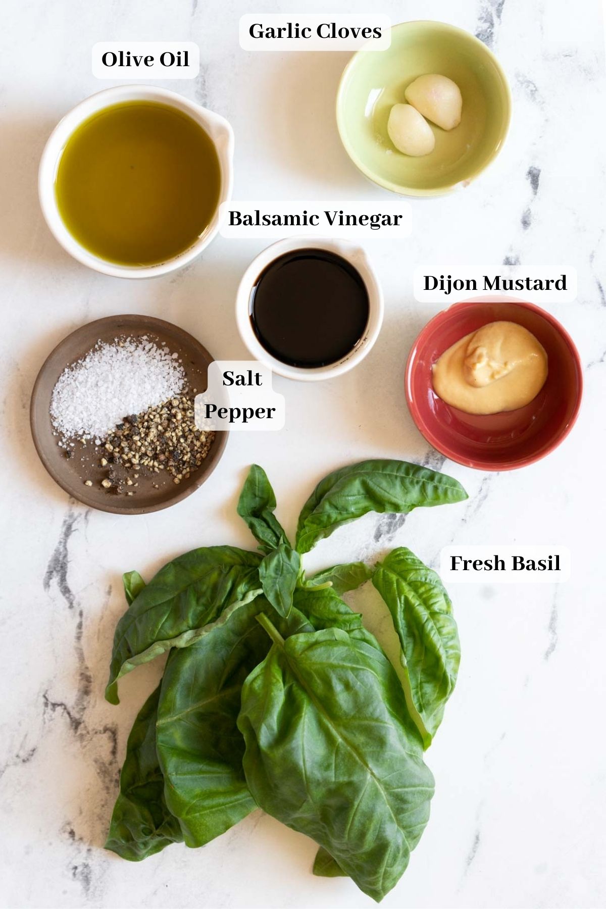 Balsamic salad dressing ingredients on a counter with fresh basil.